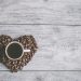 coffee filled white ceramic mug beside brown coffee beans on beige wooden surface