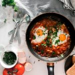 tomato soup on black cooking pan beside stainless steel fork and bread knife